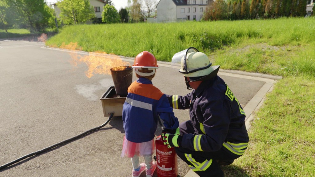 Foto: Feuerwehrmann und Mädchen löschen kleines Feuer