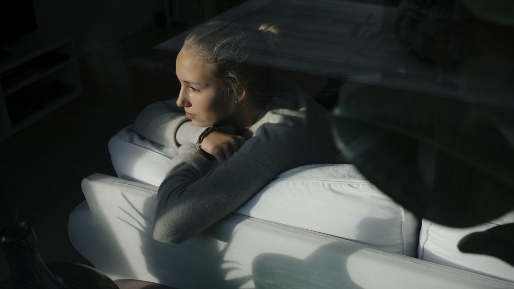 Eine junge Frau liegt auf dem Sofa und schaut zum Fenster