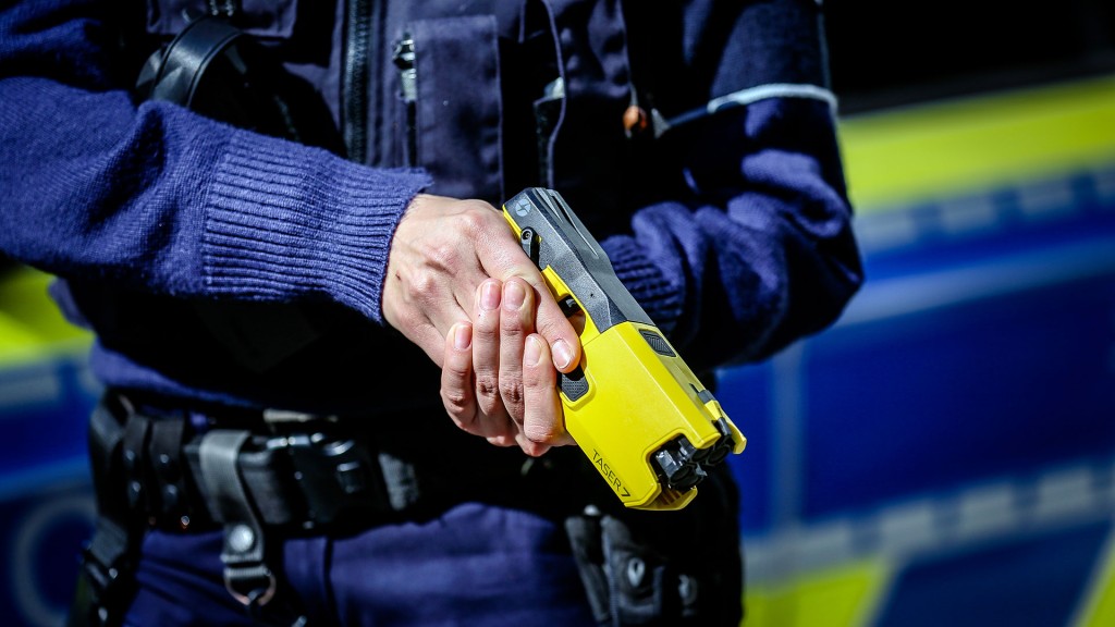 Eine Polizistin hält einen Taser in den Händen