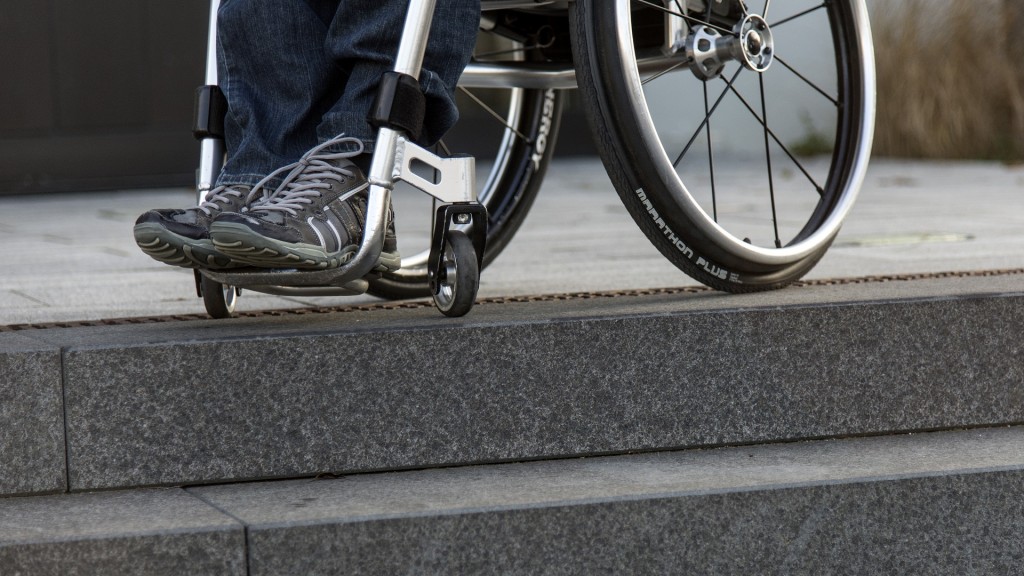 Ein Rollstuhlfahrer steht in seinem Rollstuhl an einer Treppe vor einem Gebäude.